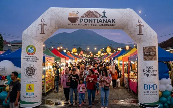 Balon gate berbentuk gerbang menghiasi pintu masuk pasar malam dengan suasana ramai pengunjung