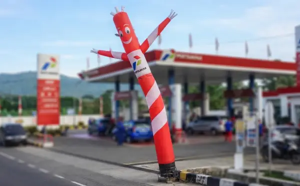 Sky dancer merah bergerak di depan area pom bensin sebagai media promosi yang menarik perhatian pengunjung.
