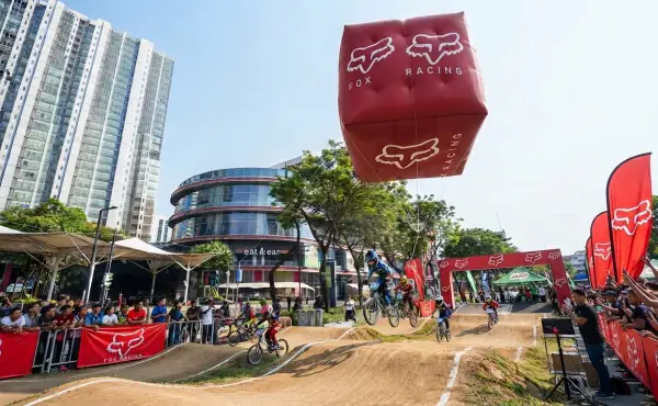 Balon udara Banjarmasin berbentuk kotak bertuliskan Fox Racing di atas lintasan perlombaan sepeda BMX di area perkotaan.