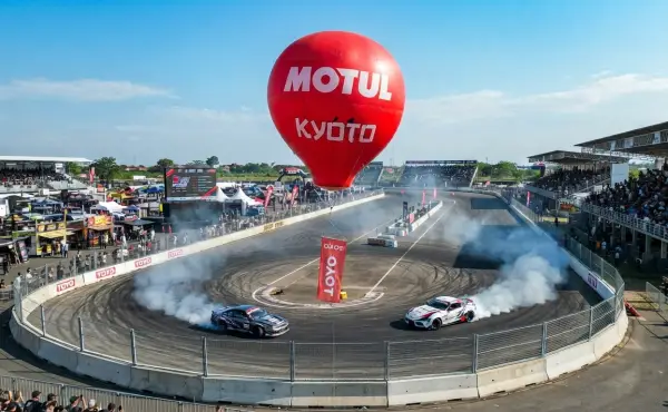 Balon udara Jambi berlogo Motul terlihat di atas lintasan saat acara balap mobil drift dengan penonton memenuhi area sirkuit.