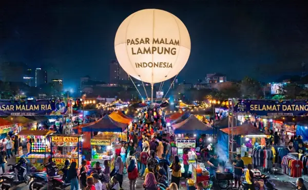 Balon udara Lampung bertuliskan Pasar Malam Indonesia terlihat di atas keramaian pasar malam pada suasana malam hari