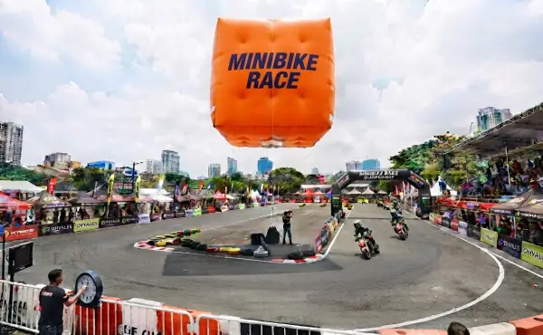 Balon promosi berbentuk kotak bertuliskan Minibike Race berada di atas lintasan perlombaan motor
